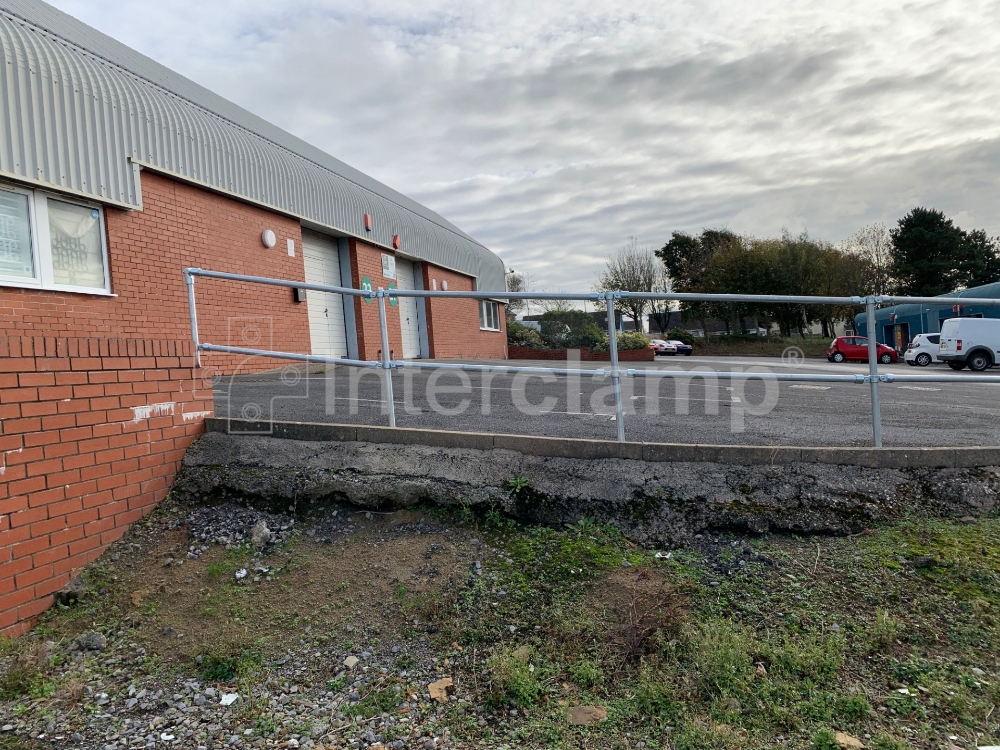 Secure guardrail at an industrial car park built with Interclamp key clamp fittings and tube, enhancing the safety of the parking environment.